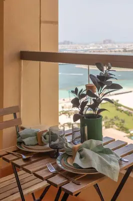 a table with plates and glasses on a table with a window at Frank Porter - Sadaf 7, JBR in Dubai