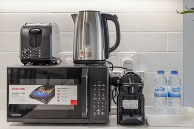 a microwave sitting on top of a counter with water bottles at Marina Horizon by LIV High Floor 1BR, For 5 Guests, Dual Gyms & Marina View in Dubai