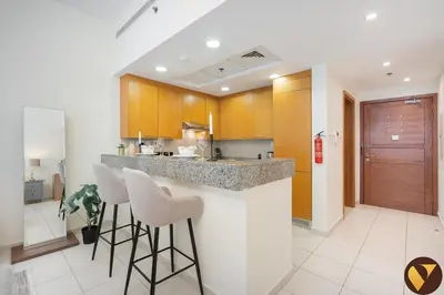 a kitchen with a counter and stools in a room at Vogue Business Bay - Bay Square Close to Downtown, Burj Khalifa and Dubai Mall, Studio Apartment with Balcony and City View, Access to all Amenities in Dubai