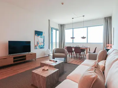 a living room with a couch and a tv and a table at HiGuests - 2 BR Escape Golf View Haven in The Greens in Dubai