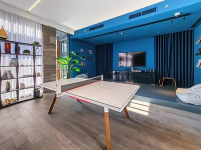 a ping pong table in a living room with blue walls at New Cozy Studio, Ideal for 2 in Kensington Waters in Dubai