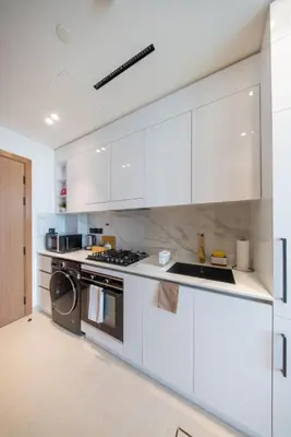 a kitchen with white cabinets and a stove at Epic Pool I JVC Studio I Fully Furnished in Dubai