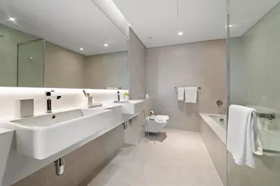a bathroom with two sinks and a toilet and a shower at Parkside 2BR plus Maid Canal Front in Dubai