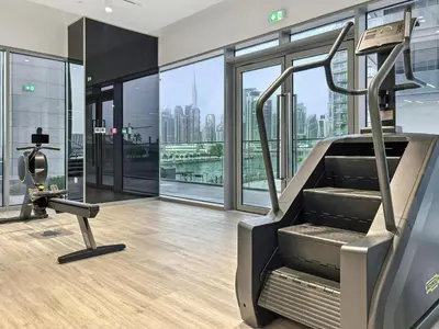 a gym with a treadmill and views of the city at Parkside 2BR plus Maid Canal Front in Dubai