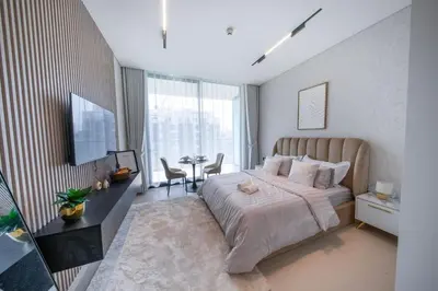 a bedroom with a large bed and a table with chairs at JVC Studio l Full Furnished I Epic Pool in Dubai