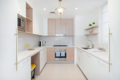 a white kitchen with white counters and white appliances at StayShort - Dubai Creek Harbour sleeps 6 in a Great Location in Dubai