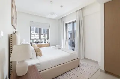 a white bedroom with a bed and a window at StayShort - Dubai Creek Harbour sleeps 6 in a Great Location in Dubai