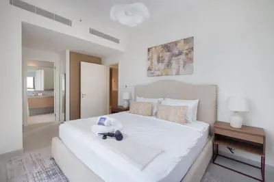 a bedroom with a white bed with a stuffed animal on it at StayShort - Dubai Creek Harbour sleeps 6 in a Great Location in Dubai
