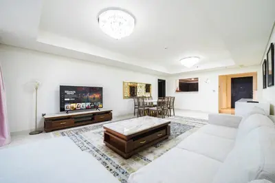 a living room with a white couch and a tv at SettlerHomes - Seaside Lux Escape With Calm Sea View in Dubai
