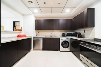 a kitchen with black cabinets and a washer and dryer at SettlerHomes - Seaside Lux Escape With Calm Sea View in Dubai