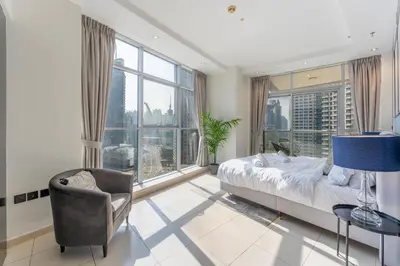 a bedroom with a bed and a chair and large windows at Luxury 3BR Dubai Marina Sea & Ain Dubai View in Dubai