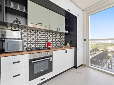 a kitchen with white cabinets and a large window at Classic Luxe 2BDR in Collective in Dubai