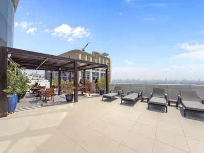 a rendering of a rooftop patio with chairs and tables at 1BR in JLT, Steps from Metro, Marina & Mall in Dubai