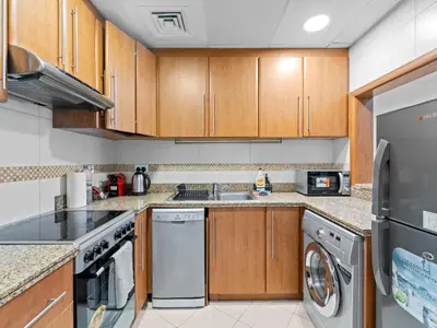 a kitchen with wooden cabinets and stainless steel appliances at 1BR in JLT, Steps from Metro, Marina & Mall in Dubai