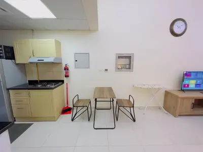 a kitchen with a table and chairs and a clock on the wall at Mahenti - Elite 1 · Large balcony with all u need in Dubai