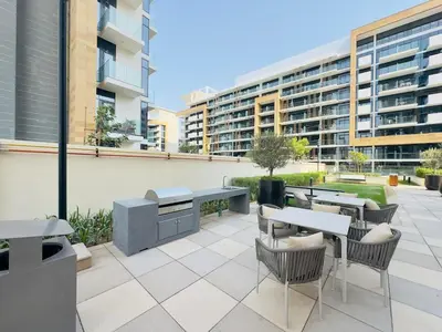 a patio with tables and chairs and a building at Mahenti – Elegant Studio Apartment | Azizi Riviera in Dubai