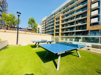 two ping pong tables on a lawn in front of a building at Mahenti – Elegant Studio Apartment | Azizi Riviera in Dubai