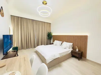 a bedroom with a bed and a table and a tv at Mahenti – Elegant Studio Apartment | Azizi Riviera in Dubai