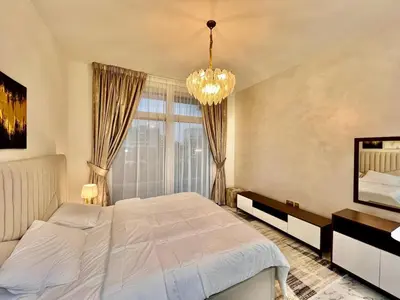 a bedroom with a large bed and a chandelier at Mahenti - Bright studio near Miracle Garden in Dubai