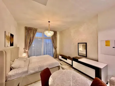 a bedroom with a large bed and a chandelier at Mahenti - Bright studio near Miracle Garden in Dubai