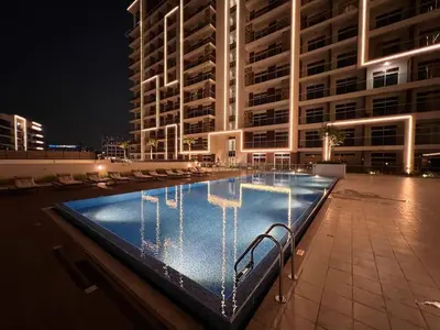 a swimming pool in front of a building at night at Mahenti - Bright studio near Miracle Garden in Dubai