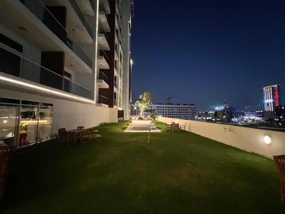 a green lawn on the side of a building at night at Mahenti - Bright studio near Miracle Garden in Dubai