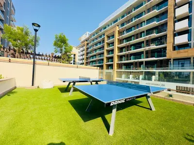 two ping pong tables on a lawn in front of a building at Mahenti - Contemporary Studio Living in Meydan in Dubai