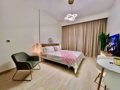 a bedroom with a bed and a chair and a tv at Mahenti - Contemporary Studio Living in Meydan in Dubai