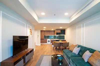 a living room with a green couch and a table at Stylish 2BR Balcony Palm Jumeirah Views in Dubai