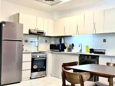 a kitchen with a table and a stainless steel refrigerator at Mahenti - 1BR - Stunning Lake & Burj Khalifa Views in Dubai