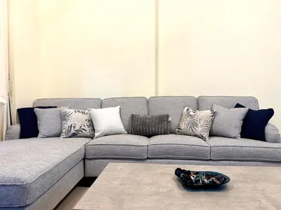 a living room with a gray couch with pillows at Mahenti - Sunlit Spacious Apartment in JVC in Dubai