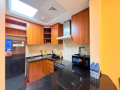 a kitchen with wooden cabinets and a black counter top at Mahenti - Bright & Cozy Studio Metro Accessible in Dubai