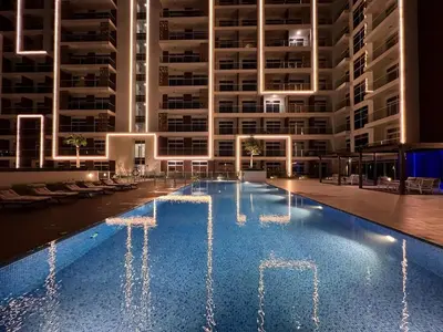 a swimming pool in front of a large building at night at Mahenti - Jewelz · With balcony easy to pool & gym in Dubai
