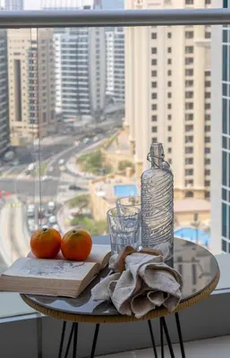 a table with two oranges and a bottle and a glass at Frank Porter - Aurora Tower, Dubai Marina in Dubai