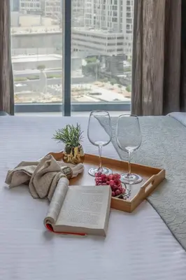 a tray with wine glasses and a book on a bed at Frank Porter - The Paragon in Dubai