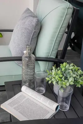 a table with a bottle and glasses and a book at Frank Porter - Samana Golf Avenue in Dubai