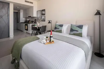 a large white bed with a bottle of wine on it at Frank Porter - Samana Golf Avenue in Dubai