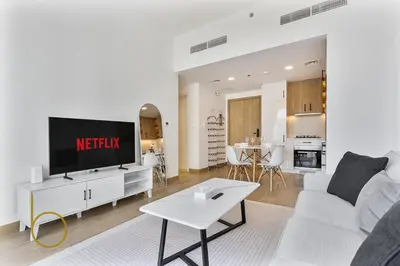 a living room with a white couch and a tv at Bookable 1 Bed Liva Tower with Pool & Garden in Dubai