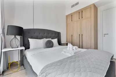a bedroom with a large bed with a wooden cabinet at Bookable 1 Bed Liva Tower with Pool & Garden in Dubai