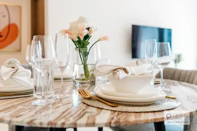 a wooden table with plates and glasses and flowers at Capital Stay - 1 Bed Apt in MBR City in Dubai