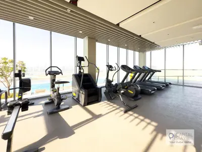 a gym with cardio equipment in a building with windows at Capital Stay - 1 Bed Apt in MBR City in Dubai