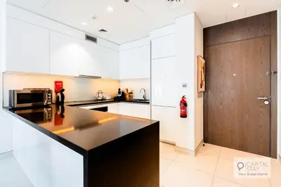 a kitchen with white cabinets and a black counter top at Capital Stay - 1 Bed Apt in MBR City in Dubai