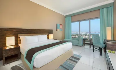 a hotel room with a bed and a dining room at Atana Hotel in Dubai