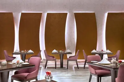 a dining room with tables and chairs and columns at Atana Hotel in Dubai