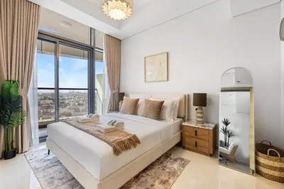 a white bedroom with a bed and a large window at Elegant 1BR Flat in Business Bay with Pool & Gym in Dubai