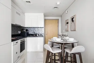 a kitchen with a small table and two stools at Elegant 1BR Flat in Business Bay with Pool & Gym in Dubai