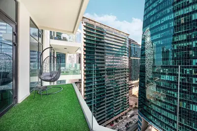 a balcony with a chair and a view of a city at Mahogany 20 - 1BR 4PAX - Infinity Pool & Spacious in Dubai