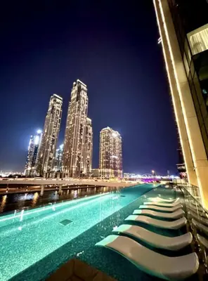 a large swimming pool at night with tall buildings at Mahogany 20 - 1BR 4PAX - Infinity Pool & Spacious in Dubai