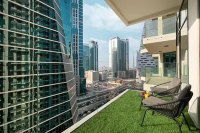 a balcony with grass and chairs and a view of the city at Mahogany 19 - 2BR 6PAX - Infinity Pool Stylish Flat in Dubai