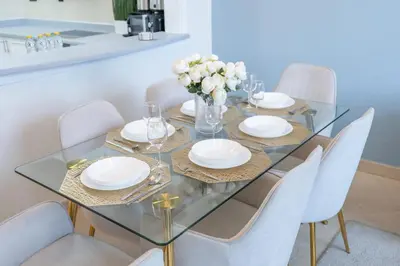 a glass dining table with white plates and flowers on it at StayShort - Premium 2BR in Dubai Marina - Sleeps 4 in Dubai